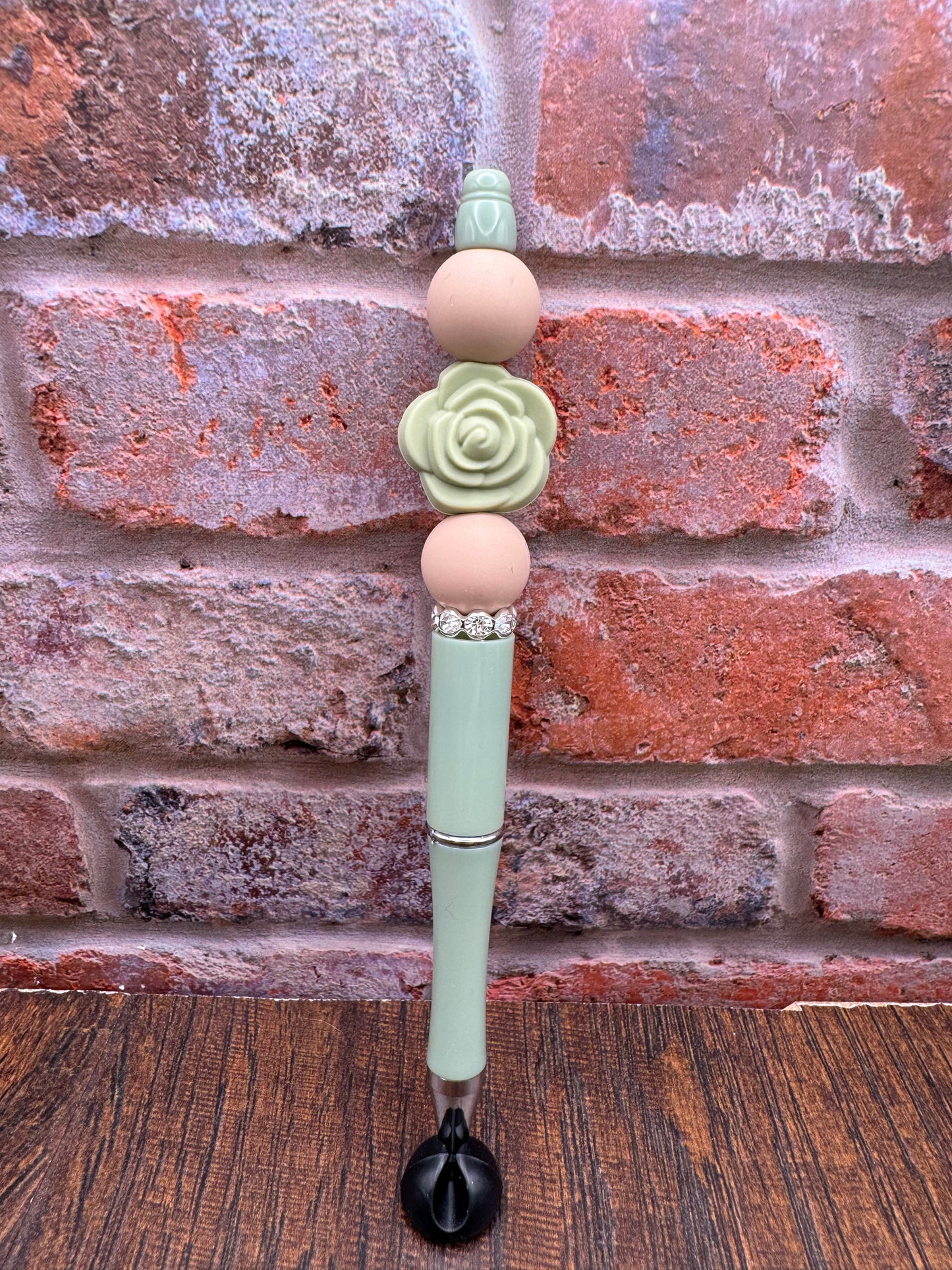 Sage green rose bloom and tan pen